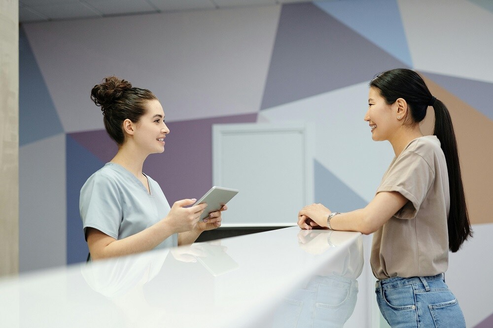 Receptionist at doctor's office talks to patient over counter